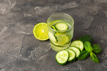 Cucumber water with lemon, lime and mint on a wooden table. Water infused with sliced...