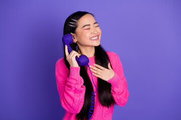 Young woman with retro styled phone laughing joyfully against vibrant purple background in trendy...