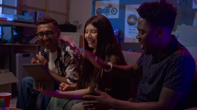 Multiethnic group of friends cheering and high five while watching sports match online via tablet