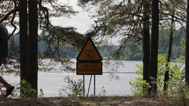 Alvkarleby, Sweden A man walks past the Dala River and a warning sign in Swedish saying: Danger Strong Currents. 