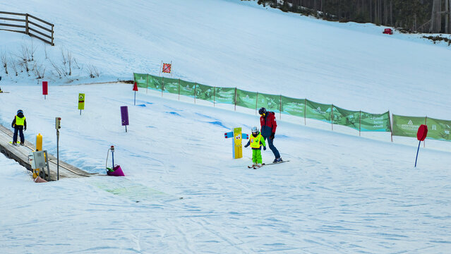 A ski instructor helps a young child learn to ski on a gentle slope at a ski resort.