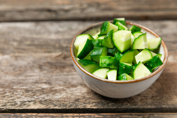 Cucumber on wooden background. Slice of cucumber on background. Fresh organic green cucumbers gherkin. Vegan. Salad ingredient. Farm vegetables. Cut vegetables with knife. Space for text. Copy space