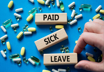 Paid Sick Leave symbol. Concept words Paid Sick Leave on wooden blocks. Beautiful blue background...
