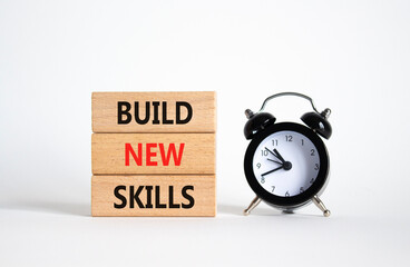 Build New skills symbol. Concept word Build New skills on wooden blocks with alarm clock. Beautiful...
