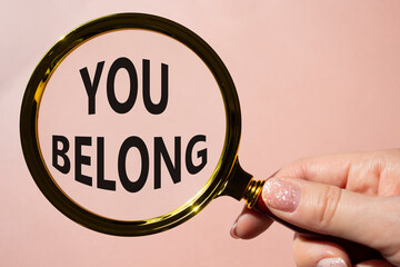 You belong symbol. Concept words You belong on magnifying glass. Beautiful pink background....