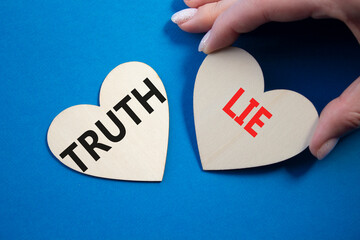Truth or Lie symbol. Concept word Truth or Lie on wooden hearts. Businessman hand. Beautiful blue...
