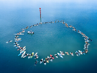 Aerial view of a gathering of paddleboarders and a boat encircling a red buoy in the turquoise waters, Western Australia, Western Australia, Australia.