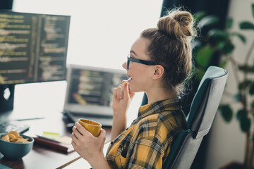 Young woman programmer working remotely in a modern home office environment with coding software on...