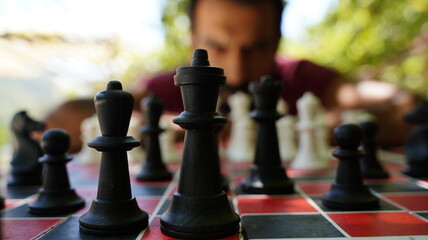 Portrait of a Serious Man Playing Chess Outdoors on a Sunny Day, Engaged in Strategic Thinking