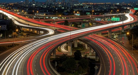 Nighttime highway interchange with light trails from vehicles long exposure shot.