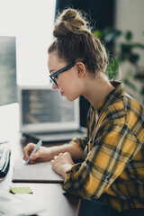 Focused young woman working in a cozy and modern workspace on coding and development projects for...