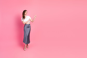 Fashionable woman in a stylish outfit pointing in front of a vibrant pink background promoting...