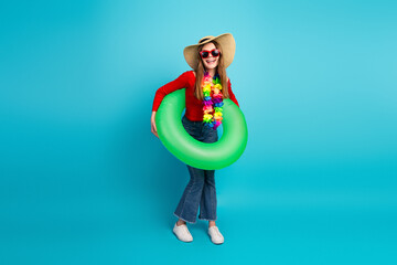 Joyful young woman in casual spring attire with vibrant accessories holding a green floatie on a...