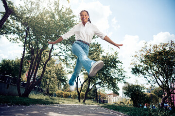 Cute woman joyfully jumping in a park during a beautiful spring day, radiating happiness and energy...