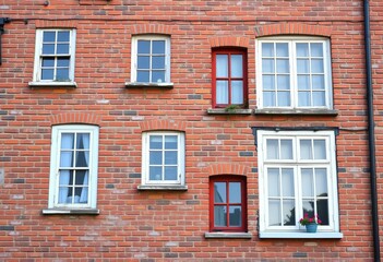 Fototapeta premium Aged brick wall with multiple college-style windows, varying sizes and shapes, old, masonry