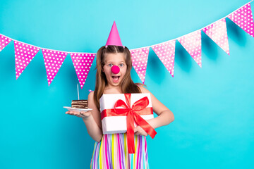 Cute schoolgirl holding a birthday gift and cake slice, celebrating cheerfully against a vibrant...