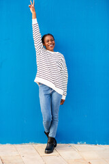 Playful African woman in striped sweater making peace sign