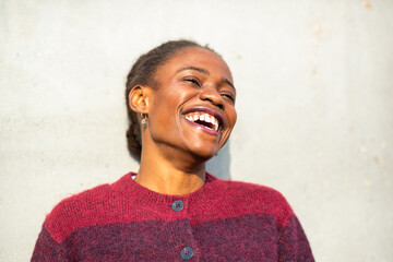 Laughing African woman enjoying sunlight in warm knit sweater
