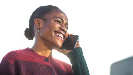 Joyful African woman on phone call under bright sky