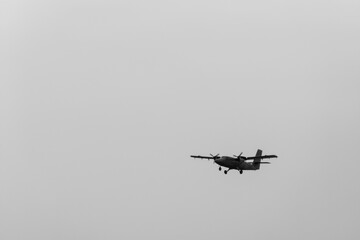 Propeller airplane in black and white flying through clear sky. Visual minimalism symbolizing...