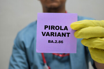Doctor holds in hands a card with the name of the new coronavirus pirola variant BA.2.86. Medical...