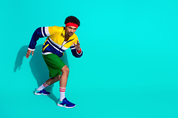 Retro styled young male athlete in vibrant activewear striking a dynamic pose against a teal...