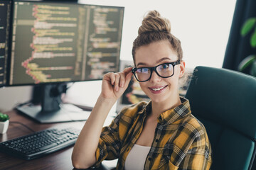 Young woman programmer in casual attire working on her computer in a home office environment,...