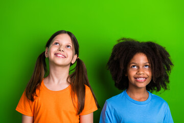 Two joyful schoolgirls enjoying their day on a vibrant green background, highlighting friendship,...