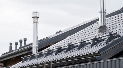 Modern roofing with solar panels and chimneys on a contemporary building under overcast skies