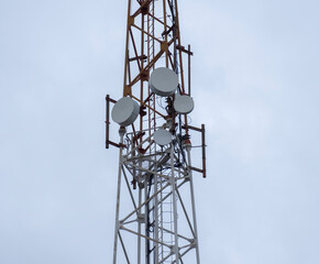 Communication tower with antennas installed under cloudy sky at urban location
