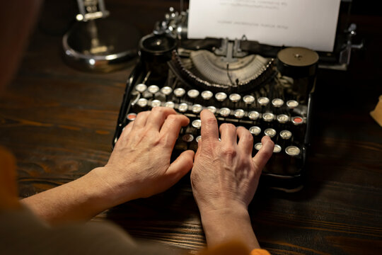 Person using a vintage typewriter to create written work in a cozy workspace setting