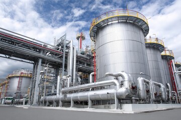 Obraz premium Large industrial plant featuring numerous tanks and piping systems located in an industrial zone under a cloudy sky