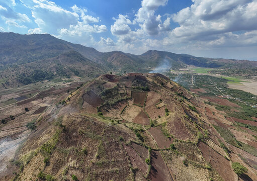 Aerial view of a volcano with terraced slopes under a bright sky, revealing the textured land, Chu Pah, Gia Lai, Vietnam.