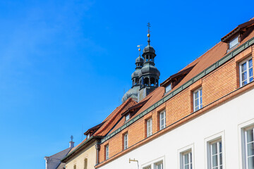 Fototapeta premium Historic german architecture with brick facade and church tower under clear blue sky