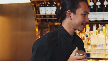 Closeup Asian hand bartender shaking mixed cocktail at luxurious counter preparation for making...