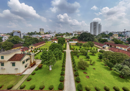 Aerial view of the Dak Lak Museum with its red-tiled roofs contrasting against the vibrant green lawns and clear blue sky, Buon Ma Thuot, Dak Lak, Vietnam.