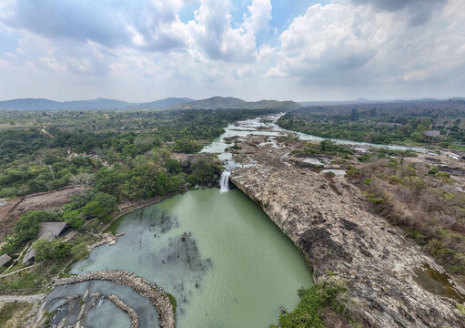 Aerial view of a cascade plunging into the jade-green waters, surrounded by lush greenery and rocky outcrops, creating a stunning contrast, Buon Ma Thuot, Dak Lak, Vietnam.