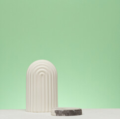 A white decorative element in an arched shape is installed on a green stone. A stage for...