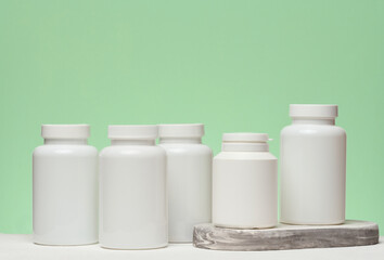 Several white plastic jars with pills on a green background. Items related to medicine and health...