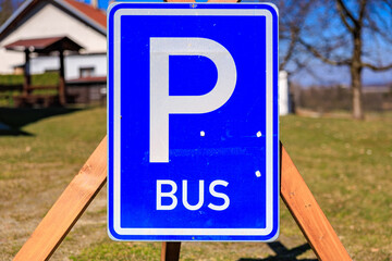Bus parking sign outdoors with green grass and house in background