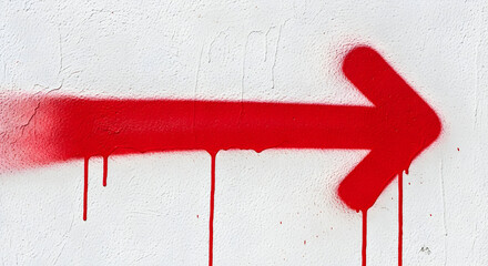 Striking red spray paint arrow on a textured white wall indicating direction