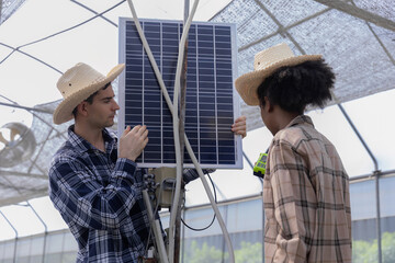 Farmer man inspecting a solar panel device for greenhouse for cultivation of vegetable food. Woman...
