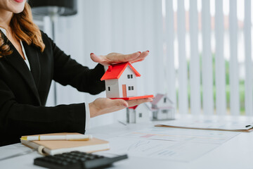 Smiling asian real estate agent showing house model during video conference with potential clients,...