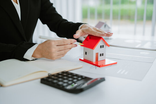Smiling asian real estate agent showing house model during video conference with potential clients, discussing property details and offering investment opportunities