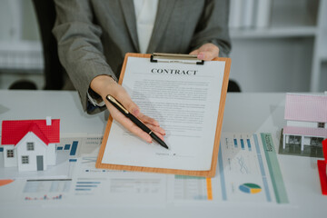 Closeup hands signing agreement document about buying home together at home, close-up hands of...