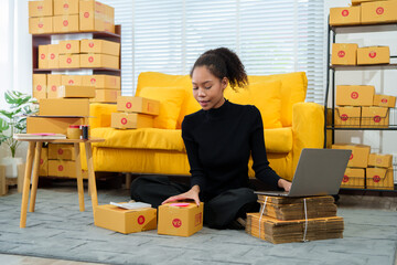 Young entrepreneur checking orders on clipboard while working in warehouse full of cardboard boxes while managing her online store business.