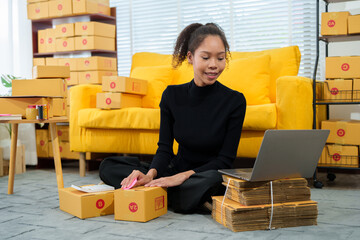 Young entrepreneur checking orders on clipboard while working in warehouse full of cardboard boxes while managing her online store business.