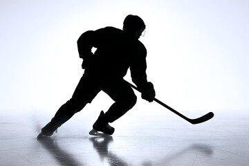 Obraz premium Silhouette of a dynamic ice hockey player mid-stride on reflective ice, backlit with glowing halo on white background. 