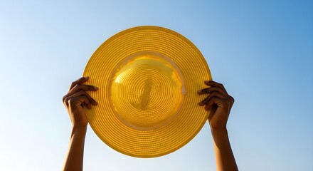 A dark-skinned man holds a yellow straw hat against a clear blue sky. The concept of a summer trip.