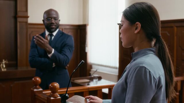 Anxious woman answering questions of African American lawyer while testifying in bright courtroom
